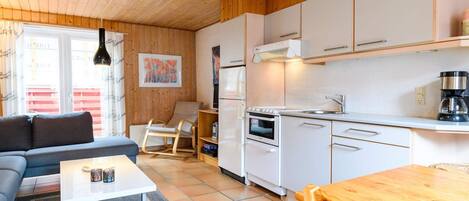 A compact living space with a kitchenette, a sofa, a dining table, and a rocking chair.