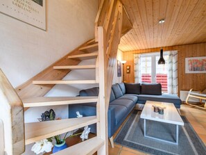 A modern interior with a wooden staircase, a sectional sofa, a white coffee table, and a window with curtains. - 4 Person Holiday Home in Fano (Fano)