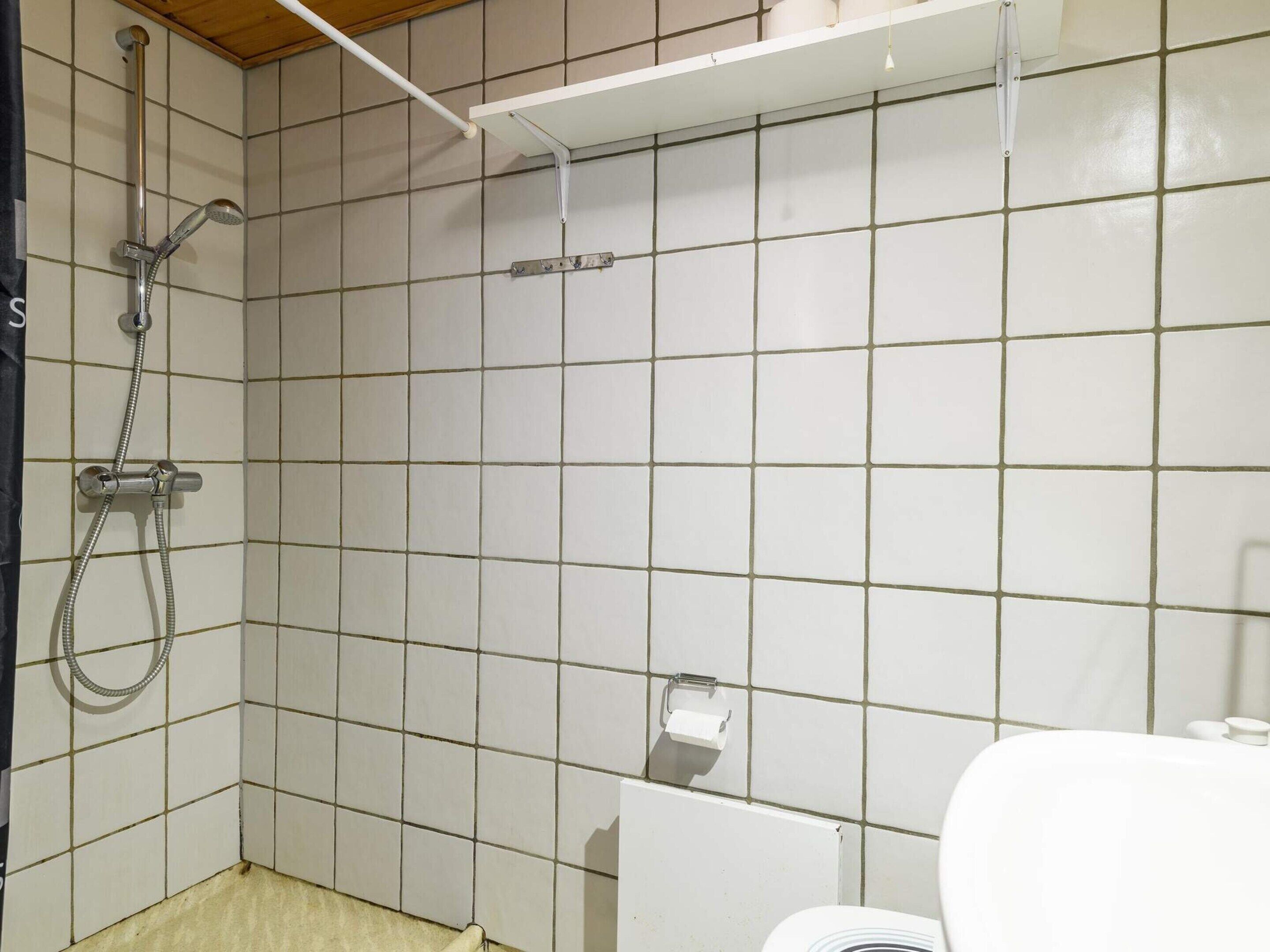 A bathroom with a shower, toilet, and a towel rack.