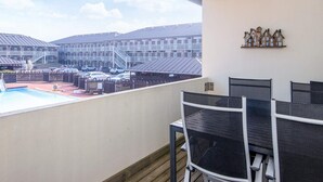 A balcony with a view of a swimming pool and a parking area, furnished with black mesh chairs and a small table. - 4 Star Holiday Home in Fano (Fano)