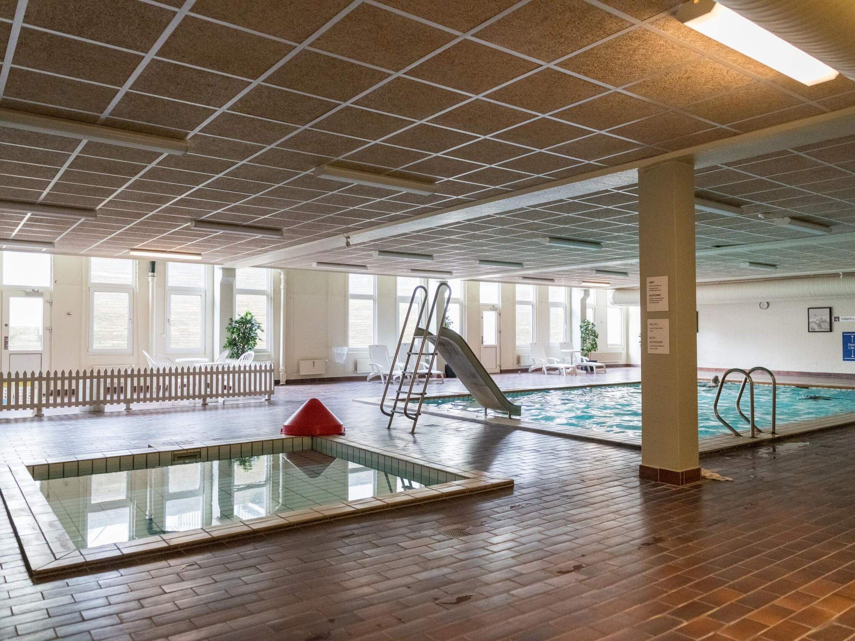 An indoor swimming pool area with a diving board, a slide, and a small pool.