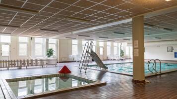 An indoor swimming pool area with a diving board, a slide, and a small pool.
