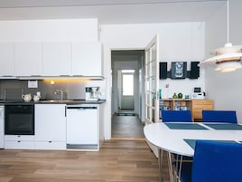 A compact kitchen with a dishwasher, coffee maker, and a dining area with a table and chairs.