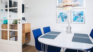 A room with a white table, blue chairs, a bookshelf, and framed artwork on the wall. - 4 Star Holiday Home in Fano (Fano)
