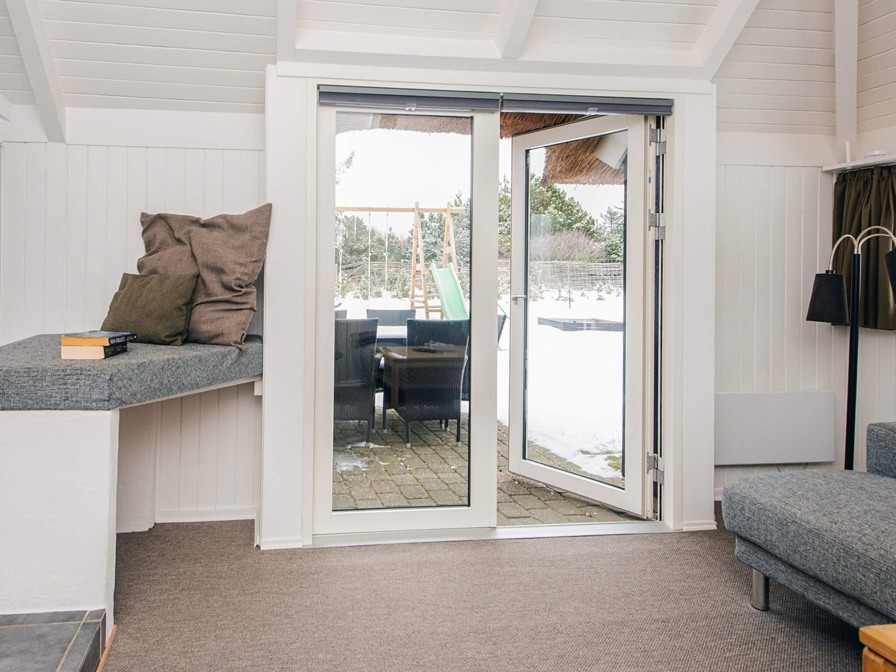 Habitación con puerta de cristal corredera que da a un espacio exterior con mesa y sillas.