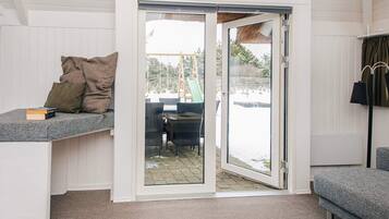 Habitación con puerta de cristal corredera que da a un espacio exterior con mesa y sillas.