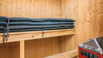 A sauna room with wooden walls, a bench, and a sauna unit.