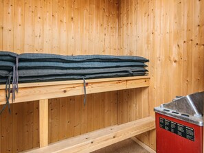 A sauna room with wooden walls, a bench, and a sauna unit. - 4 Star Holiday Home in Vejers Strand (Vejers Strand)