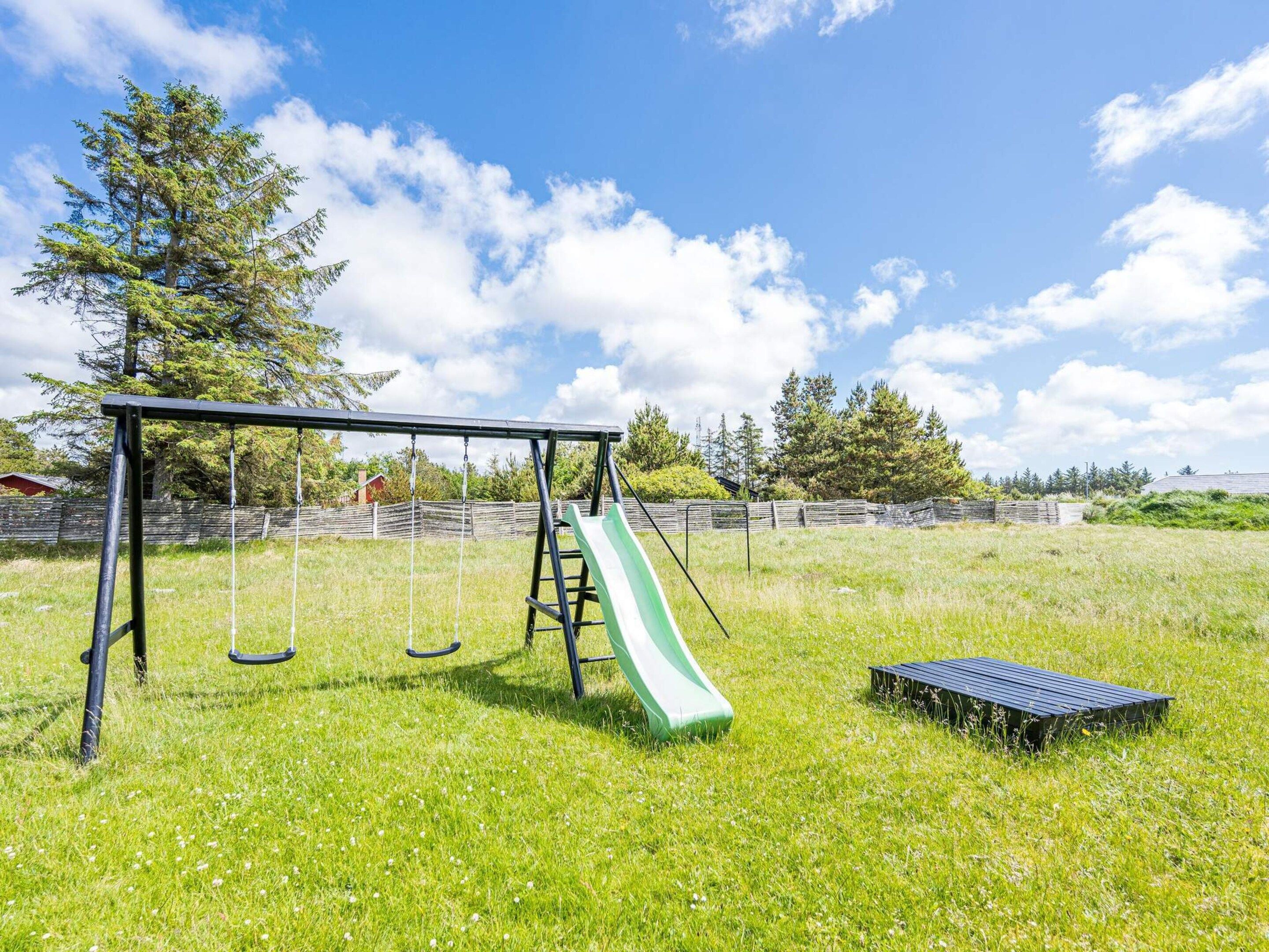 A playground with a swing set and a slide in a grassy field.