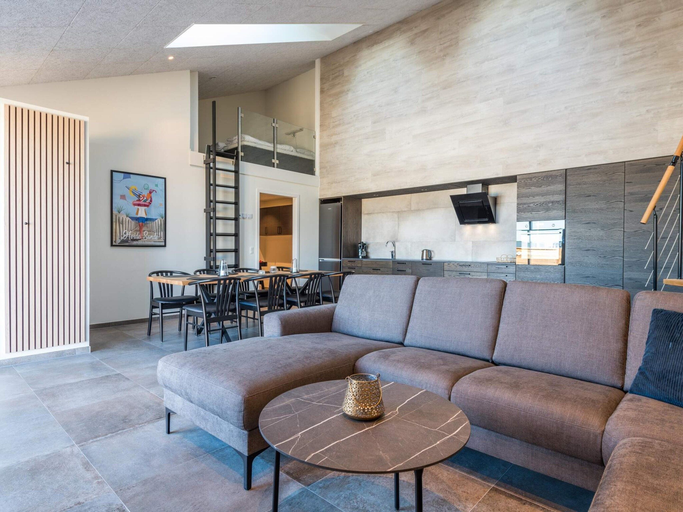 Un salon moderne avec un canapé d’angle, une table basse ronde et un coin repas comprenant des chaises et une table.
