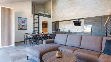 A modern living room with a sectional sofa, a round coffee table, and a dining area with chairs and a table.