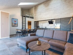 Un saló modern amb un sofà seccional, una taula de centre rodona i una zona menjador amb cadires i taula.