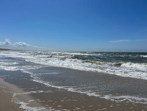 A beach with waves, a clear sky, and a distant shoreline.