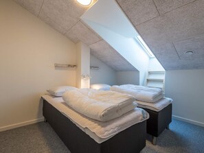 A bedroom with two beds, a skylight, and a small shelf. - 6 Person Holiday Home in Hvide Sande (Hvide Sande)