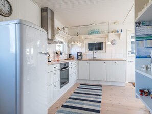 A modern kitchen with white cabinetry, a stainless steel range hood, a built-in oven, a microwave, and a coffee maker. - 4 Person Holiday Home in Fano (Fano)