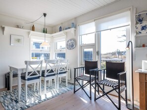 A dining area with a table and chairs, a patterned rug, and a view through a glass door. - 4 Person Holiday Home in Fano (Fano)