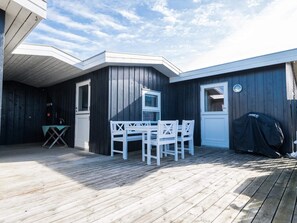A wooden deck with a table and chairs, a grill, and a door with a window. - 4 Person Holiday Home in Fano (Fano)