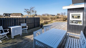 An outdoor deck with white furniture, a wooden fence, and a view of the surrounding landscape. - 4 Person Holiday Home in Fano (Fano)
