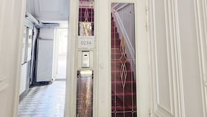 En storslagen hall med en kristallkrona, en trappa och en dörr med skylten ”Hotell, tredje våningen, rum 0234”.