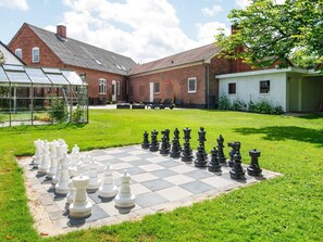 A chessboard set up on a lawn with a brick building in the background. - 8 Person Holiday Home in Norre Nebel (Norre Nebel)