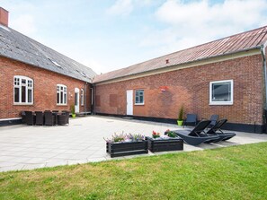 A courtyard with a brick building, outdoor seating, and planters. - 8 Person Holiday Home in Norre Nebel (Norre Nebel)