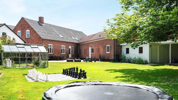 Un jardin avec un trampoline, un jeu d’échecs et une serre.