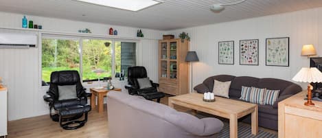 A cozy living room with a sofa, chairs, a table, and a cabinet.