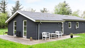 A dark-colored single-story building with a sloped roof, a covered patio with outdoor seating, and a number '15' on the side. - 6 Person Holiday Home in Veslos (Vesløs)