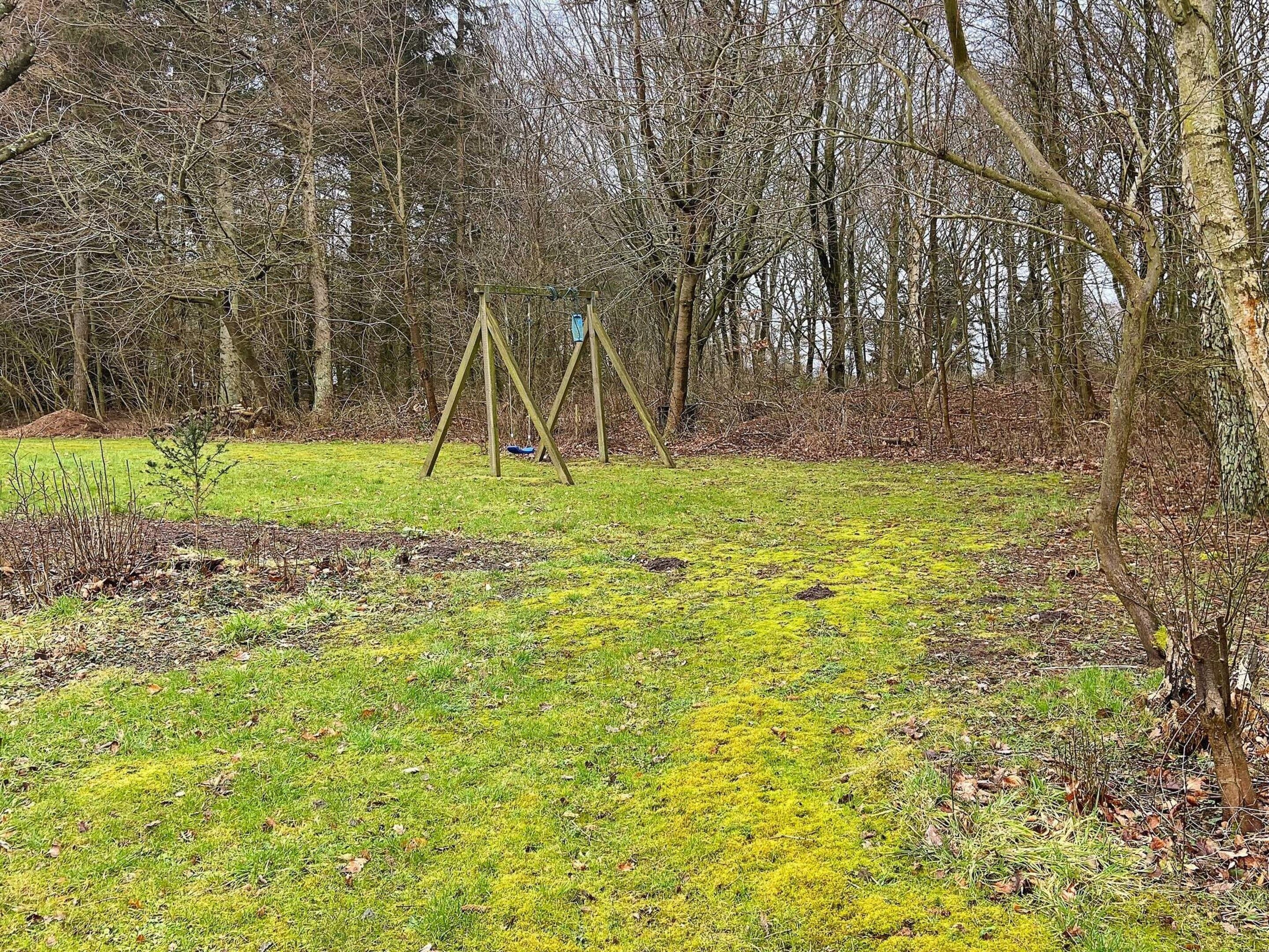 A grassy area with a swing set and trees in the background.