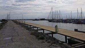 Una marina amb embarcacions amarrades, un moll de fusta i una riba rocosa.