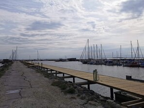Un port de plaisance avec des bateaux amarrés, une jetée en bois et une côte rocheuse.