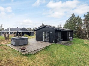 A modern house with a deck, a hot tub, and a small outdoor seating area. - 4 Star Holiday Home in Hadsund (Hadsund)