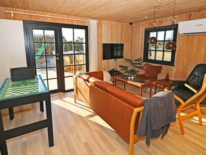 A furnished living room with a sofa, chairs, a coffee table, a chess table, and a television. - 4 Star Holiday Home in Hadsund (Hadsund)