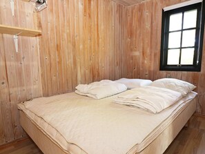A room with wooden walls, a bed with white bedding, and a window with blinds. - 4 Star Holiday Home in Hadsund (Hadsund)