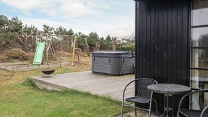 A patio with a hot tub, outdoor seating, and a slide.