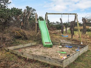A playground with a green slide and swings. - 4 Star Holiday Home in Hadsund (Hadsund)