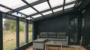 A modern interior with a sectional sofa, a wooden coffee table, and a glass door leading outside. - 4 Star Holiday Home in Hadsund (Hadsund)
