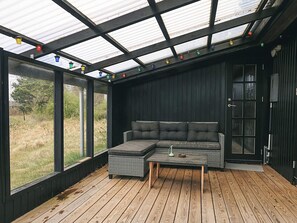 A modern interior with a sectional sofa, a wooden coffee table, and a glass door leading outside. - 4 Star Holiday Home in Hadsund (Hadsund)