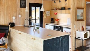 A modern kitchen with a central island, wooden cabinetry, and a black backsplash. - 4 Star Holiday Home in Hadsund (Hadsund)