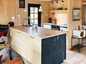 A modern kitchen with a central island, wooden cabinetry, and a black backsplash. - 4 Star Holiday Home in Hadsund (Hadsund)