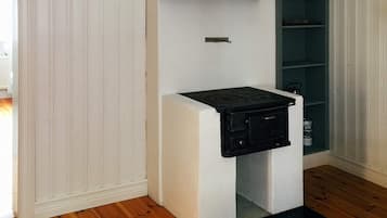A compact kitchen with a built-in stove, white cabinetry, and a wooden floor.
