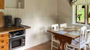 A kitchen with a wooden table, white chairs, a coffee maker, and a microwave.