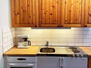 A kitchen with wooden cabinets, a Bosch coffee maker, a sink, and a Husqvarna stove. - 3 Person Holiday Home in Eskilstuna (Eskilstuna)