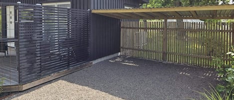 Un bâtiment moderne à l’extérieur sombre, doté d’un espace extérieur couvert et d’une allée en gravier.
