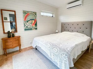 A bedroom with a bed, a dresser, a mirror, a poster, and an air conditioning unit. - 4 Star Holiday Home in Farhult (Hoganas)