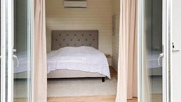 A bedroom with a bed, curtains, and an air conditioning unit.
