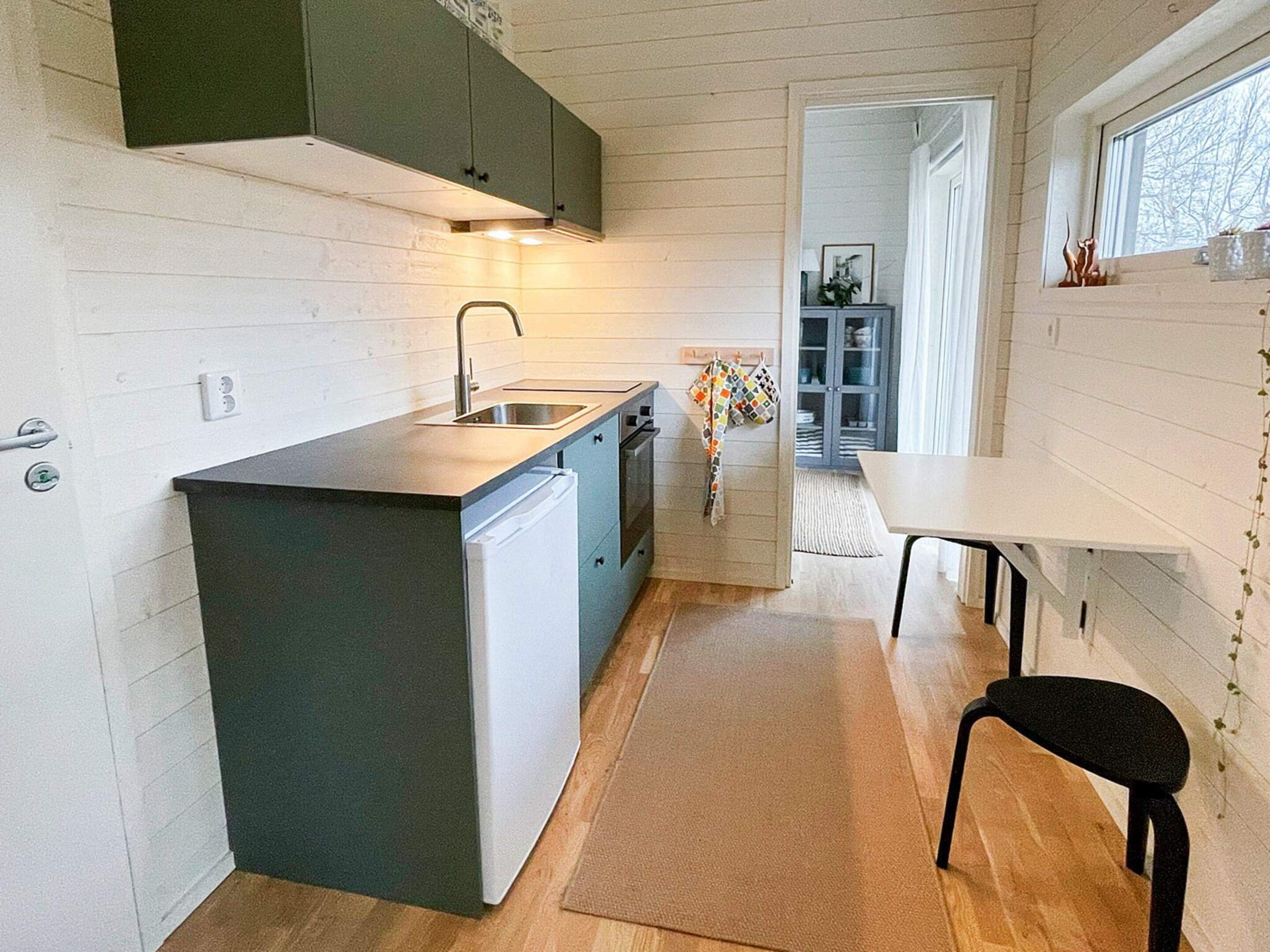 Una cocina compacta con lavavajillas integrado, una pequeña isla y ventana con vista a un jardín.