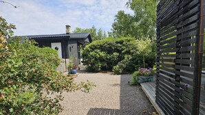 A gravel pathway leading to a house with a dark roof and a chimney. There are potted plants and a wooden fence on the left. - 4 Star Holiday Home in Farhult (Hoganas)
