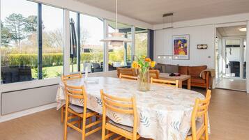 A dining area with a table and chairs, a vase with flowers, and a sofa.