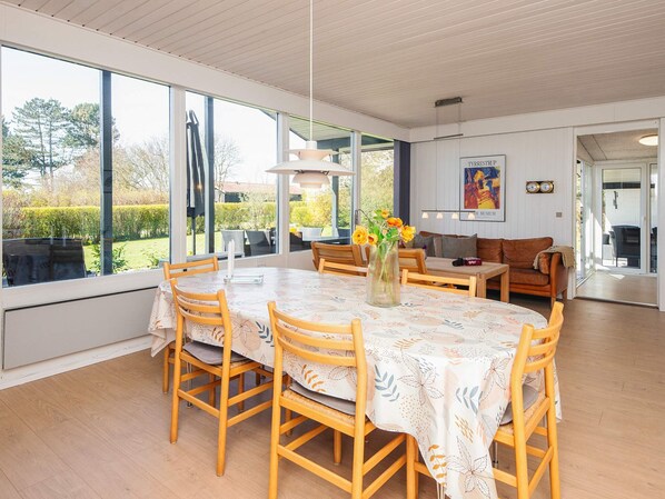 A dining area with a table and chairs, a vase with flowers, and a sofa.